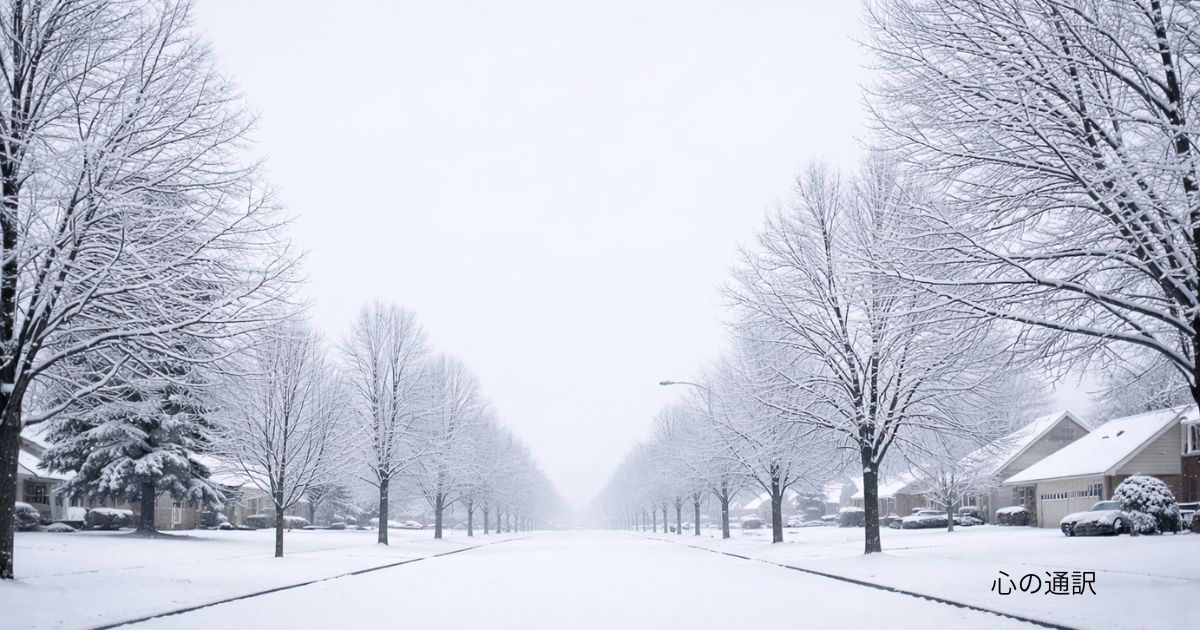 雪に覆われた静かな住宅街の並木道。白い曇り空の下、まっすぐな道が奥へと続いている。